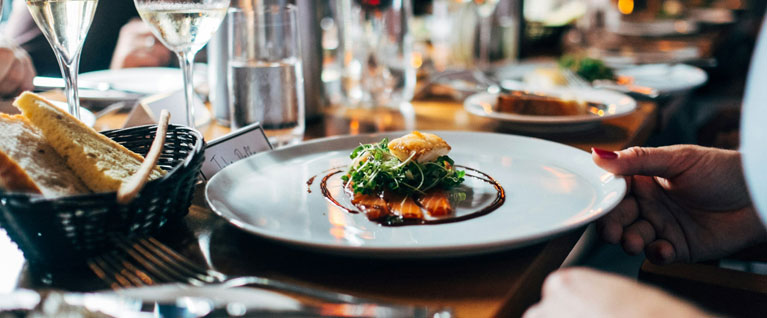 Frontage of a luxury holiday cottage with opened double doors and outdoor seating 
